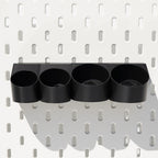 Schwarze Pegboard Schiene mit vier Rundhaltern an weißer Lochwand